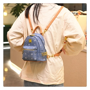 Detail of blue denim backpack with cute cartoon bear prints and golden rivet accents