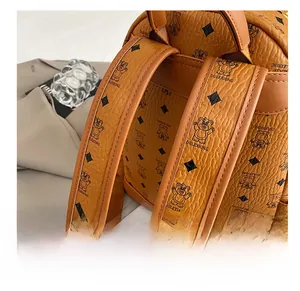 Close-up of padded shoulder straps and bear print on a brown faux leather backpack
