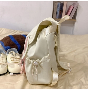 Detail of cute rabbit ears on beige student backpack with functional side drawstring pocket