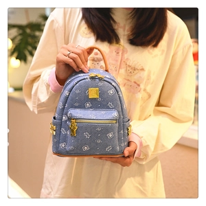 Close-up of blue denim mini backpack with cute white bear prints and gold bear pendant