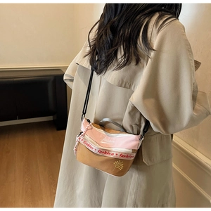 Detailed embroidery of gold leaf and fashion text on a canvas crossbody shoulder bag