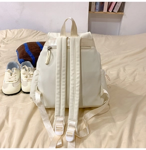 Detail view of cream backpack featuring anti-theft back zipper and padded shoulder straps