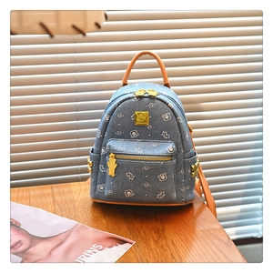 Detail of denim mini backpack featuring cartoon bear print and premium gold hardware