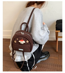 Detailed view of vintage dark brown corduroy mini backpack on person with dog patch