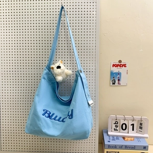 Détail du sac en toile bleu clair avec broderie Bludy et breloque ours en peluche