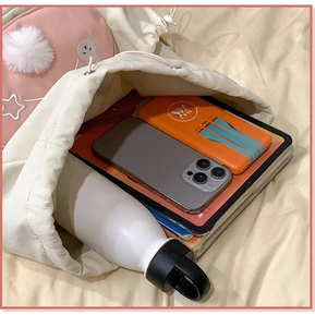 Detail of spacious beige drawstring backpack interior storing phone, tablet, and water bottle