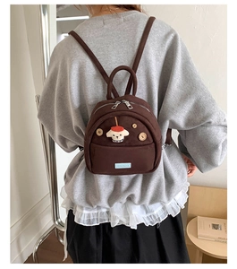 Rear view of model wearing a mini brown canvas backpack with a cute puppy cartoon design