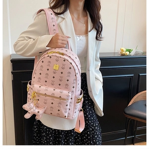 Pink backpack detail showing cute bear print, gold studs, and puppy charm accessory