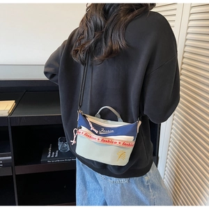 Detailed view of canvas crossbody bag showing color block design and leaf embroidery