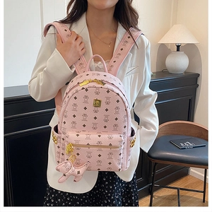 Detailed view of pink mini backpack with bear pattern, gold studs, and puppy charm