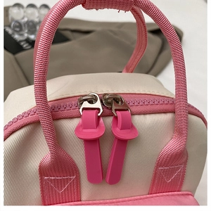 Dettaglio dello zaino mini per bambini con doppia cerniera rosa e manico intrecciato