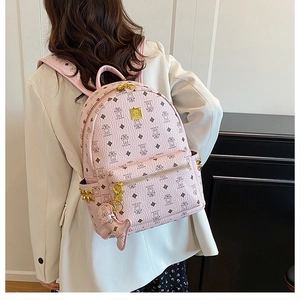 Detail of pink backpack with bear pattern, gold logo plaque and metallic cone studs