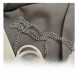 Detail of silver chain strap and lychee grain white leather texture of mini pillow bag