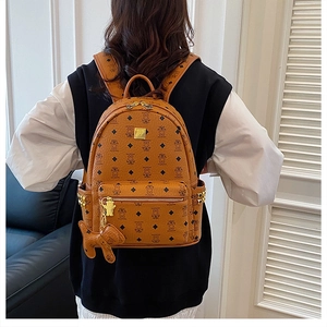 Detail of caramel leather backpack featuring bear prints and golden logo plaque