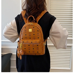 Detail view of brown backpack with bear pattern, gold zippers, and bear-shaped pendant