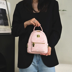 Pink mini backpack with cute bear print and golden bear charm in a lifestyle setting
