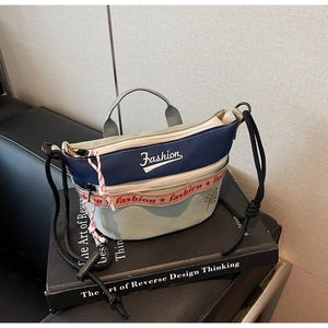 Detail of color-block canvas crossbody bag featuring Fashion lettering and adjustable rope strap