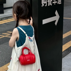 Detail of red mini cylinder crossbody bag with pearl accent and silver chain strap