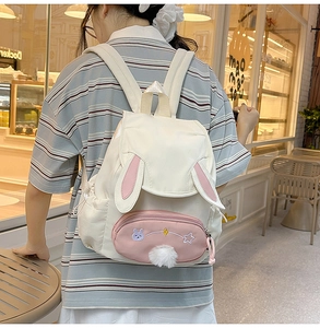 Close-up of white and pink bunny-ear backpack with cute rabbit embroidery and plush tail
