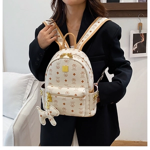 Detailed shot of white leather backpack with cute bear patterns and gold logo accents