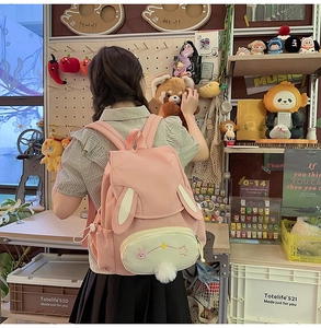 Detailed view of pink bunny-themed backpack featuring rabbit ears and plush star charms