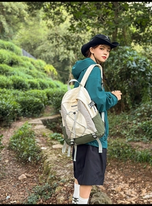 Detalle de mochila de senderismo multicolor con cordones elásticos en un bosque verde