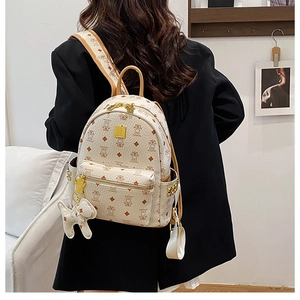 Macro detail of cream-colored backpack with bear print, gold zippers and side rivets