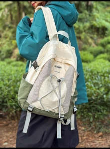 Detalle de mochila para exterior con cordones elásticos y hebilla sobre tejido de nailon verde