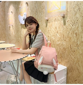 Close-up of pink bunny backpack with 3D ears and plush tail on a female model