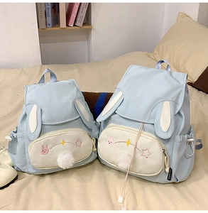 Detail of two light blue school backpacks with bunny ears and star embroidery decorations