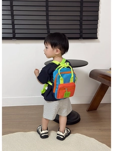 Dettaglio dello zaino per bambini color-block con tasca arancione e cinghie in nylon