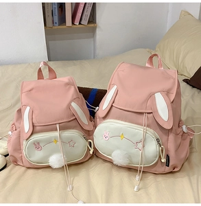 Detailed view of pink bunny backpack with white ears, star embroidery and plush pom pom