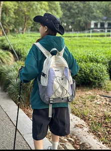 Mochila para exterior con paneles blanco-violeta y cordones cruzados en un jardín