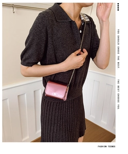 Close-up of pink metallic crossbody bag with gold chain strap on model