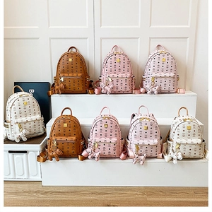 Close-up of stylish mini backpacks with classic pattern, rivets and cute dog charms