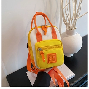 Detail of color-block mini backpack in yellow and white with woven orange handles
