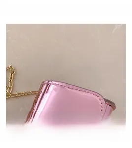 Detailed close-up of pink glossy patent leather surface with gold chain and stitching