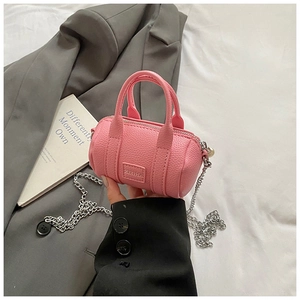 Macro detail of pink cylindrical mini bag with pebble leather texture and metal chain