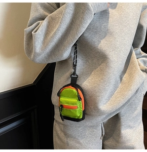Détail du mini porte-monnaie sac à dos vert néon et orange porté par un mannequin
