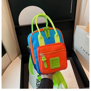 Dettaglio di un mini zaino in nylon colorato con tasca arancione e manico verde