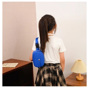 Blue nylon kids fanny pack shown on model in a cozy home setting with books and lamp