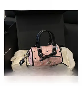 Détail du sac à main rose avec nœud, pendentif en cœur et poignée en cuir noir