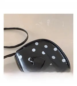 Macro shot of polka dot pattern and glossy heart clasp on the mini crossbody bag