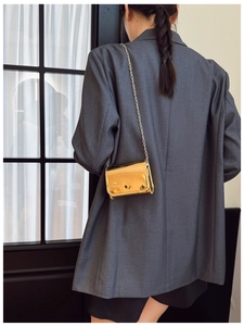 Detail of a mini gold crossbody bag with metallic mirror finish and thin chain strap