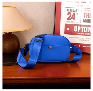 Blue kids crossbody bag with wide strap and snap pocket in cozy interior setting