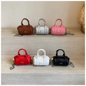 Mini cylindrical bags in six colors with chain straps and pearl charms on stone steps