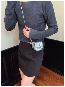 Close-up of a silver polka dot heart crossbody bag worn by a young child model