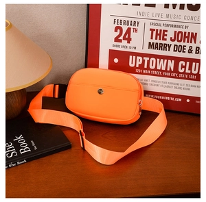 Macro shot of bright orange nylon kids fanny pack with metal zipper on dark wood surface