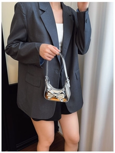 Detail of silver laser mirror handbag featuring a large bow and Y2K aesthetic