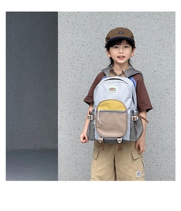 Detailed side view of children's grey and yellow color-block school backpack on a model